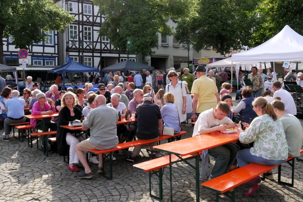 Menschen sitzen auf Bänken beim Feierabendmarkt Warburg.