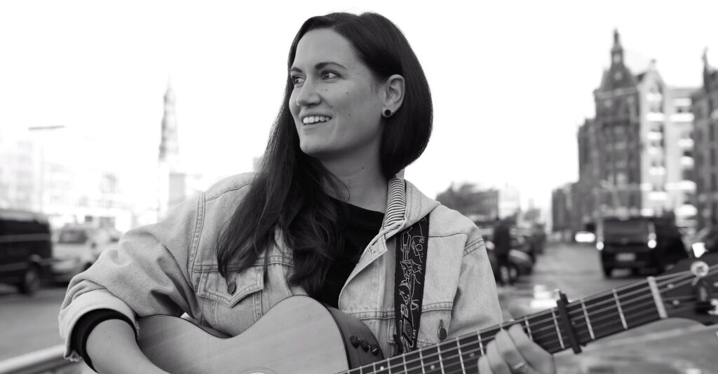 Singer-Songwriterin Maura mit Gitarre.