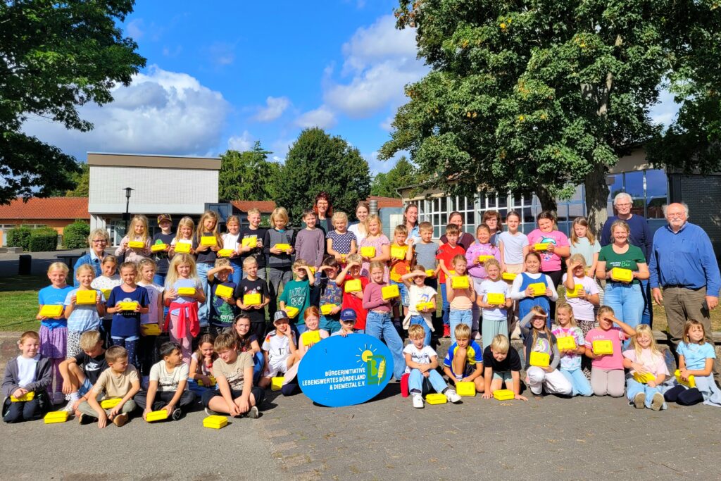 60 Kinder der Grundschule Borgentreich mit gelben Brotboxen, die sie von der Bürgerinitiative überreicht bekommen haben.
